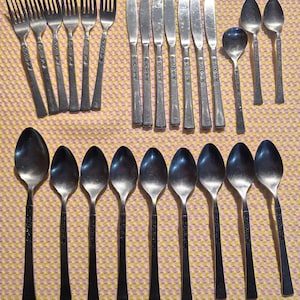 May include: A set of stainless steel silverware, including forks, knives, and spoons. The silverware has a simple design with a floral pattern on the handles.