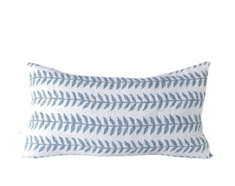 May include: A white lumbar pillow with a blue leaf pattern. The pillow is made of a soft, textured fabric.