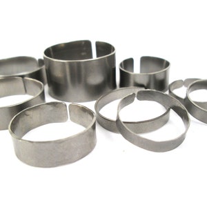 Peut inclure: Un ensemble de sept anneaux en métal argenté de différentes tailles. Les anneaux sont tous lisses et ont un bord légèrement arrondi.