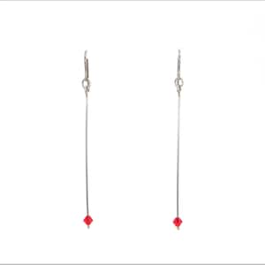 May include: A pair of silver earrings with a red crystal at the bottom of each earring.