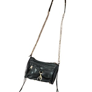 May include: A black leather crossbody bag featuring a silver-tone chain and leather strap, a front zippered pocket with a prominent silver lobster clasp closure, and two long leather zipper pulls hanging from the sides of the main compartment.
