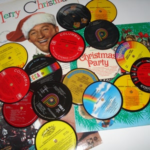May include: A collection of vintage Christmas-themed vinyl records and album covers. The records feature colorful labels with text like "Christmas Party" and "Merry Christmas." Album covers display festive imagery, including a Santa Claus hat and a Christmas tree.