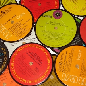 Puede incluir: Una colección de discos de vinilo vintage con etiquetas coloridas. Los discos presentan nombres de artistas como Willie Nelson, Merle Haggard y Eddy Arnold. Las etiquetas son de varios colores, incluyendo rojo, naranja y verde.