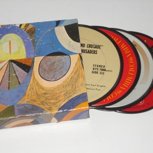 May include: A vintage record album with a colorful abstract art cover. The album contains several vinyl records with red and white labels. The labels read "Columbia" and "STEREO". The album is a music collectible.