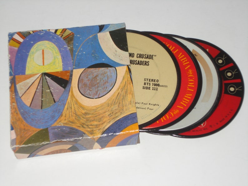 May include: A vintage record album with a colorful abstract art cover. The album contains several vinyl records with red and white labels. The labels read "Columbia" and "STEREO". The album is a music collectible.