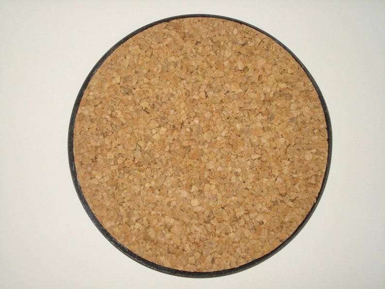 May include: Round cork coaster with a black border. The coaster is made of natural cork material, displaying a light brown, textured surface. This coaster is designed to protect surfaces from drink condensation.