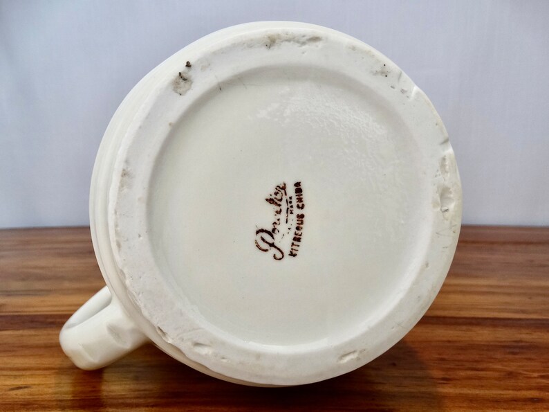 May include: The base of a white ceramic mug with a brown "Porcelite Vitreous China" stamp.