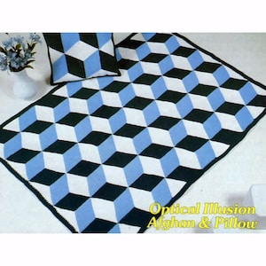 May include: A blue, white, and black crocheted afghan and pillow with an optical illusion pattern. The text "Optical Illusion Afghan & Pillow" is printed below the afghan.