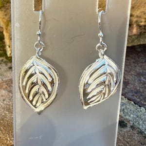 May include: A pair of silver leaf-shaped dangle earrings. The leaves have a detailed, textured design.