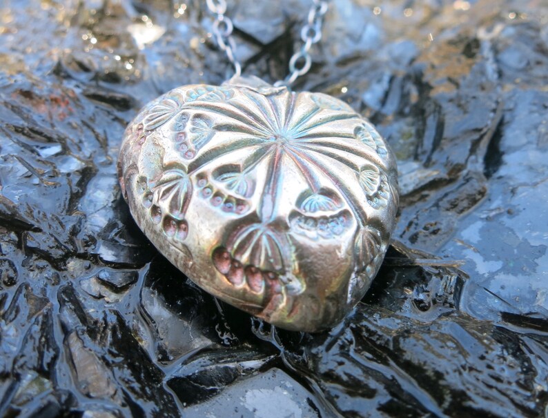 hollow form heart pendant with blue patina. Fine silver