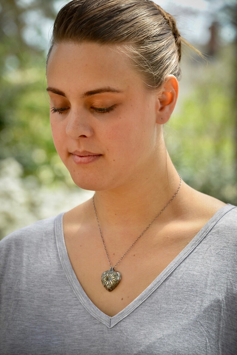 hollow form heart pendant with blue patina. Fine silver