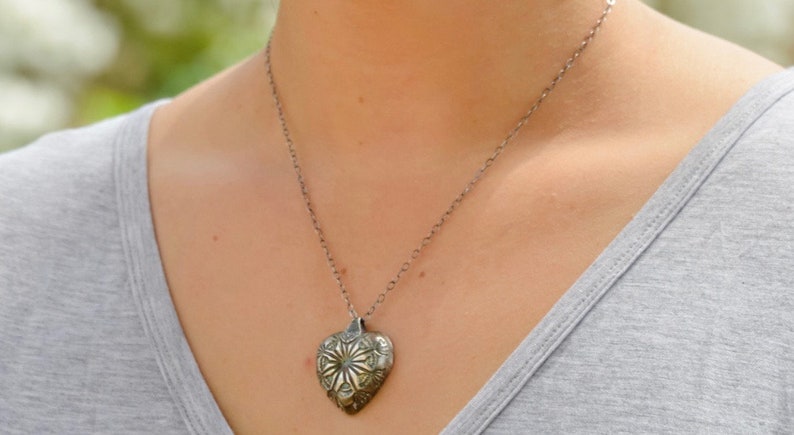 hollow form heart pendant with blue patina. Fine silver