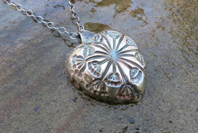 hollow form heart pendant with blue patina. Fine silver