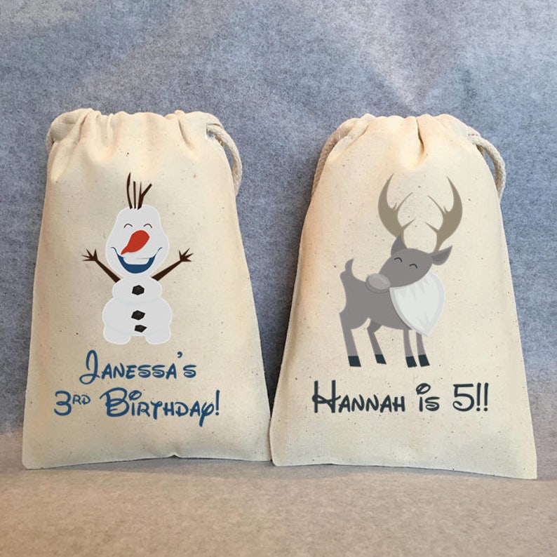 Puede incluir: Dos bolsas de cord&oacute;n de algod&oacute;n blanco con texto e im&aacute;genes personalizados. La bolsa de la izquierda tiene una imagen de dibujos animados de Olaf de Frozen y el texto "Janessa's 3rd Birthday!" La bolsa de la derecha tiene una imagen de dibujos animados de un reno y el texto "Hannah is 5!!"