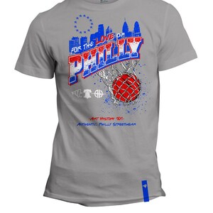 May include: A grey t-shirt with a blue and red graphic design featuring the words "For the Love of Philly" and a basketball going through a net. The graphic also includes a skyline of Philadelphia and the Liberty Bell. The text "Art History 101: Authentic Philly Streetwear" is printed below the graphic.
