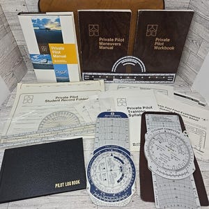 Libros antiguos de entrenamiento de pilotos privados, plotters de navegación y computadoras de vuelo.