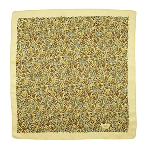 May include: A cream-colored silk scarf with a brown and blue floral pattern. The scarf has a small label with the text "Made in France" in the bottom right corner.