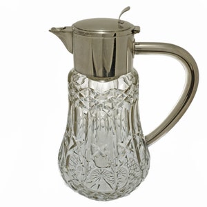 May include: A clear glass pitcher with a cut glass design and a silver lid and handle.