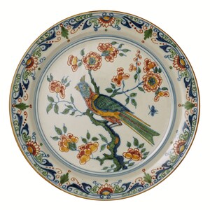 May include: A decorative ceramic plate with a bird and floral design. The plate features a colorful parrot perched on a branch with orange and yellow flowers. The rim has a blue and green floral pattern with a gold edge.