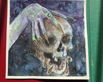May include: Watercolor painting of a skull with a skeletal hand reaching down. The hand is pale green with long, sharp, yellow nails. The skull is detailed with dark eye sockets and a partially open jaw, set against a dark blue starry background.