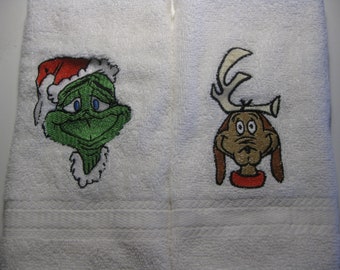 May include: White bath towel with embroidered images of the Grinch wearing a Santa hat and Max the dog wearing reindeer antlers.