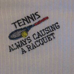 May include: White embroidered towel with a tennis racket and ball, and the text "Tennis Always Causing A Racquet".