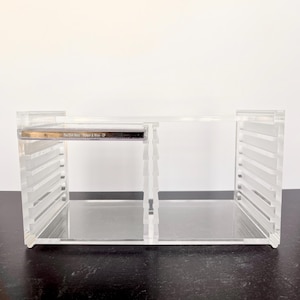 Może przedstawiać: Przezroczysty akrylowy uchwyt na płyty CD z dwoma przegrodami. Uchwyt ma prostokątny kształt z poziomymi liniami po bokach. Tekst "The Civil Wars - Poison & Wine - EP" jest widoczny na płycie CD wewnątrz.