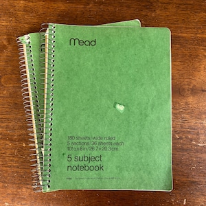 May include: Two green spiral-bound notebooks with the brand name "Mead" visible. Each notebook has 180 wide-ruled sheets, 5 sections, and measures 10.5 x 8 inches. The text "5 subject notebook" is printed on the cover.