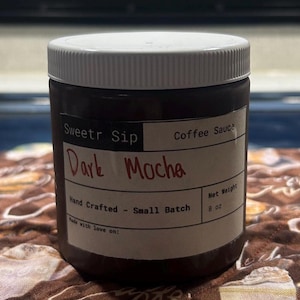 Peut inclure: Un pot de sauce au café Dark Mocha avec un couvercle et une étiquette blancs. L'étiquette indique "Sweetr Sip" et "Hand Crafted - Small Batch". Le pot contient 227 grammes de sauce.