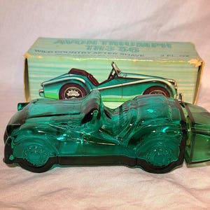 Puede incluir: Una botella vintage de vidrio verde con forma de coche de Avon Wild Country After Shave. La botella es una réplica detallada de un coche deportivo Triumph TR3. La caja detrás de la botella presenta una ilustración de coche a juego.