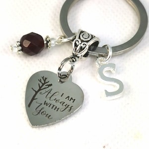 Puede incluir: Llavero de plata en forma de corazón con las palabras "I am Always With You" grabadas en él. El llavero también incluye un pequeño dije de plata con la letra "S" y una cuenta de cristal rojo oscuro.