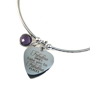 May include: Silver bangle bracelet with a heart charm that says "Fabulous shoes take you to fabulous places". The charm is attached to a small purple gemstone.