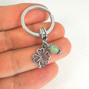 May include: Silver four-leaf clover charm with a green gemstone bead attached to a silver key ring.