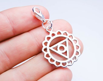May include: Silver charm with a circle design featuring a triangle with a circle inside. The charm has a lobster clasp.