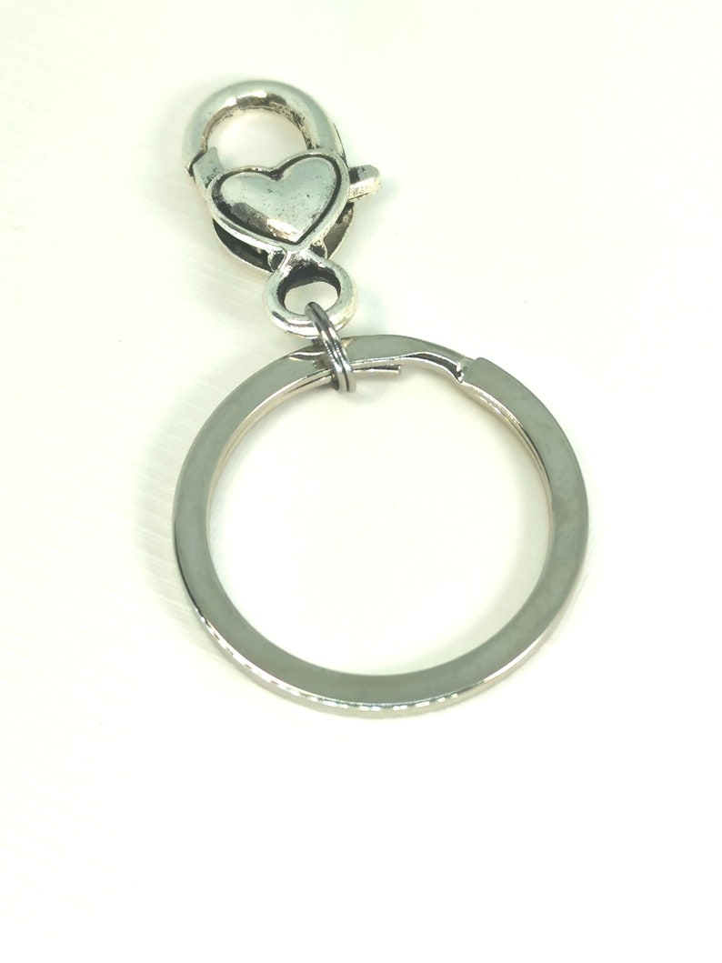 May include: A silver key chain with a heart-shaped clasp and a round ring.