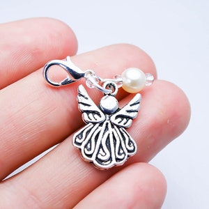 May include: Silver angel charm with a pearl and crystal beads attached to a silver lobster clasp.