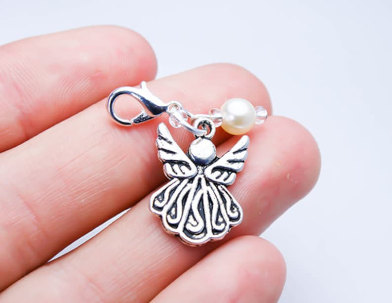 May include: Silver angel charm with a pearl and crystal beads attached to a silver lobster clasp.