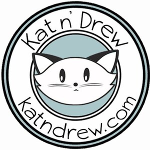 May include: Black and white illustration of a cat with a cute expression inside a circle with the text "Kat'n Drew katndrew.com" in black.