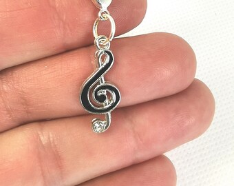 Pode incluir: Berloque de prata com um design de clave de sol preta e um strass transparente. O berloque tem um fecho de lagosta.