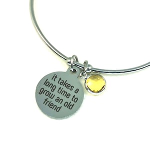 Può includere: Braccialetto rigido in argento con un ciondolo che recita "Ci vuole molto tempo per diventare un vecchio amico". Il ciondolo ha un piccolo cristallo giallo.