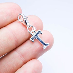 May include: Silver charm with a letter T pendant and a lobster clasp.
