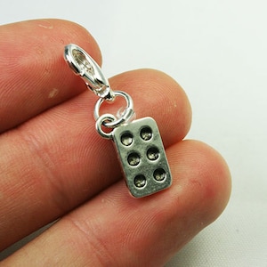 May include: Silver charm shaped like a baking pan with nine round indentations. The charm has a silver lobster clasp.