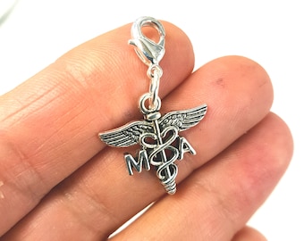 May include: Silver charm with a medical caduceus symbol and the letters "M.A." attached to a silver lobster clasp.