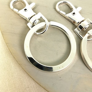 May include: Two silver keychains with a swivel clasp and a large round ring.