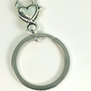 May include: Silver key chain with a heart-shaped clasp and a round ring.