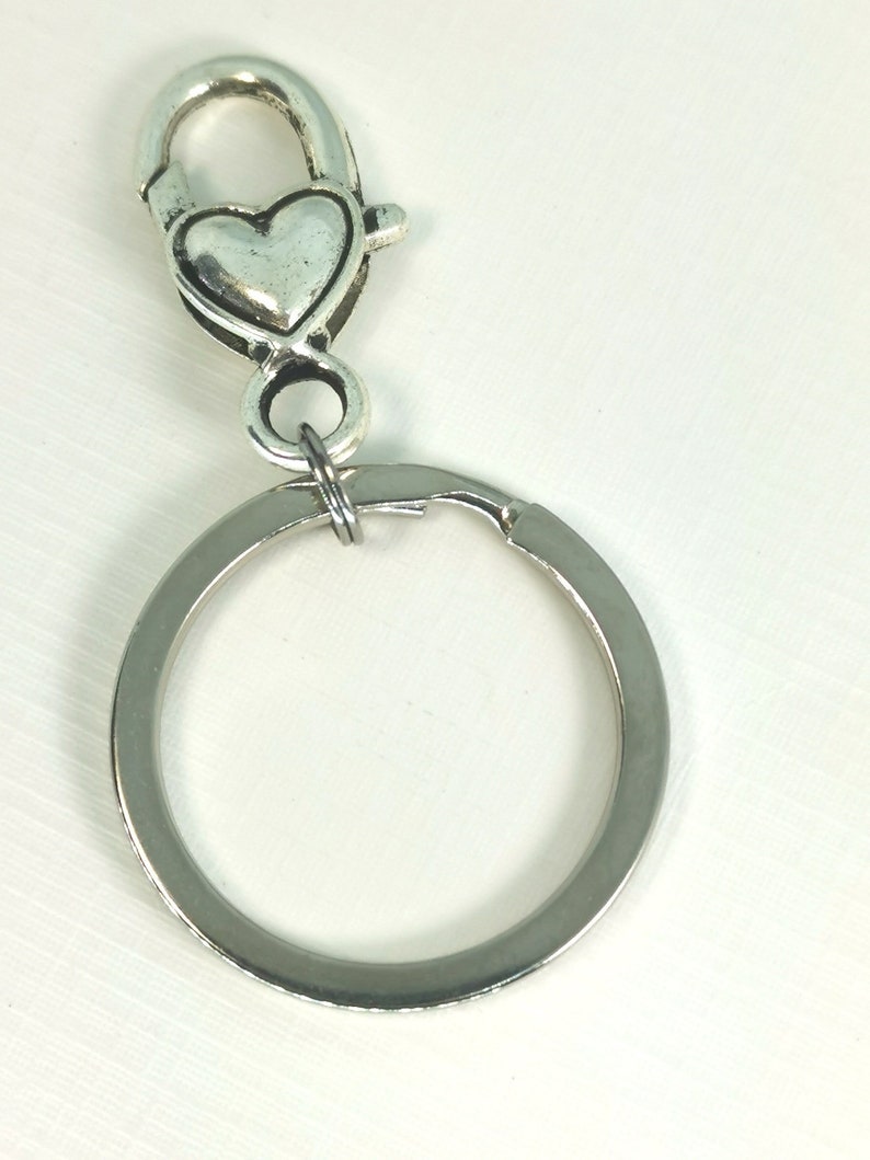 May include: Silver key chain with a heart-shaped clasp and a round ring.