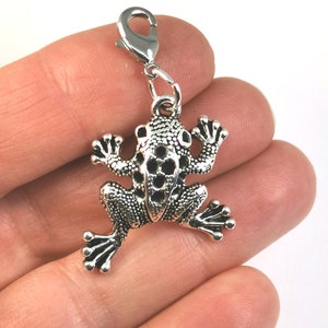 May include: Silver frog charm with a textured surface and detailed legs. The charm has a lobster clasp for attaching to a necklace, bracelet, or other jewellery.