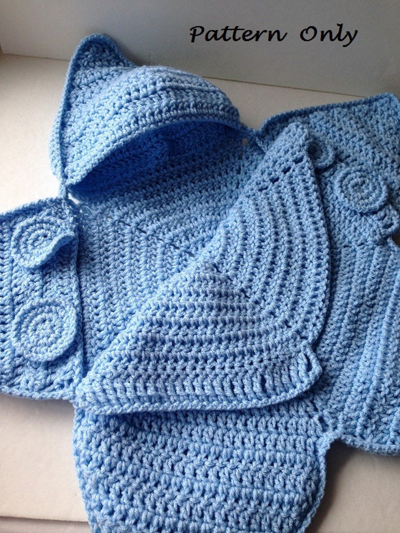May include: A light blue crocheted baby blanket with a hood. The blanket is folded in half, showing the hood and the body of the blanket. The blanket is made with a simple stitch pattern.