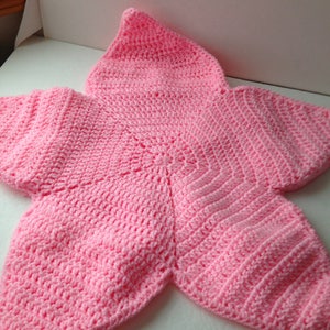May include: A pink crocheted baby blanket shaped like a star with a pointed hood.