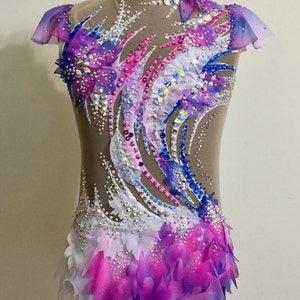 May include: A beige leotard with a high neck and sheer sleeves, adorned with a vibrant design of blue, pink, and purple accents. The costume is embellished with sparkling rhinestones and layered fabric, creating a dynamic and elegant look.